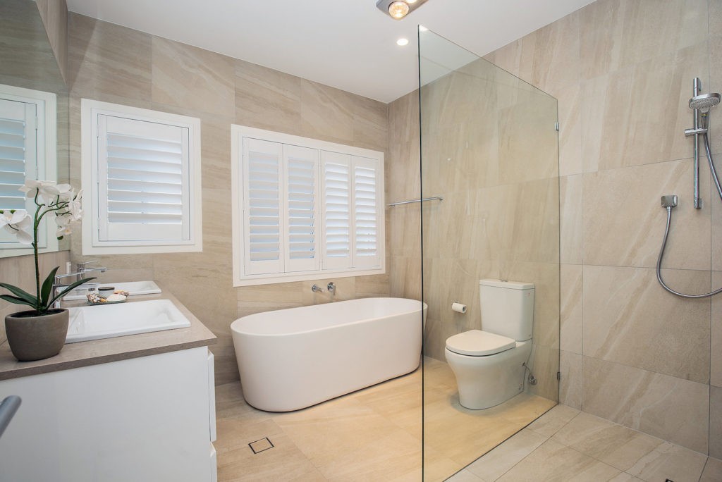 new bathroom with sandstone looking tiles, freestanding bath, double sink vanity and detachable shower head